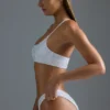Oh Polly Costumi da Bagno: Top bikini a fascia monospalla decorato HOTFIX Edition in bianco Oh Polly Costumi da Bagno: Top bikini a fascia monospalla decorato HOTFIX Edition in bianco