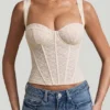 Top a corsetto con ferretti in pizzo Junia, colore avorio Top a corsetto con ferretti in pizzo Junia, colore avorio
