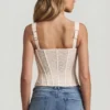Top a corsetto con ferretti in pizzo Junia, colore avorio Top a corsetto con ferretti in pizzo Junia, colore avorio