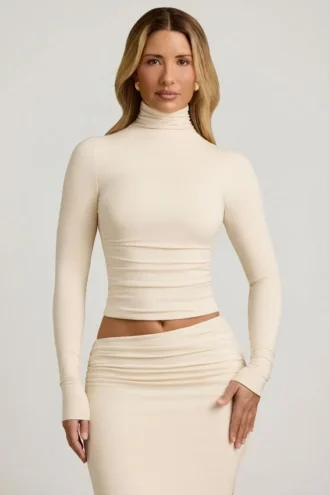 Top Auri in Modal con collo alto, ruches e schiena scoperta, colore avorio
