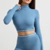 Top corto a maniche lunghe con collo alto e schiena scoperta in blu acciaio Top corto a maniche lunghe con collo alto e schiena scoperta in blu acciaio