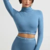 Top corto a maniche lunghe con collo alto e schiena scoperta in blu acciaio Top corto a maniche lunghe con collo alto e schiena scoperta in blu acciaio