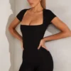 Tuta Bea con maniche ad aletta e scollo quadrato in nero Tuta Bea con maniche ad aletta e scollo quadrato in nero